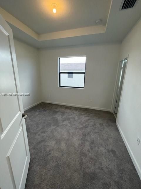 Room featuring a tray ceiling, wall-to-wall carpeting, and a single-pane window