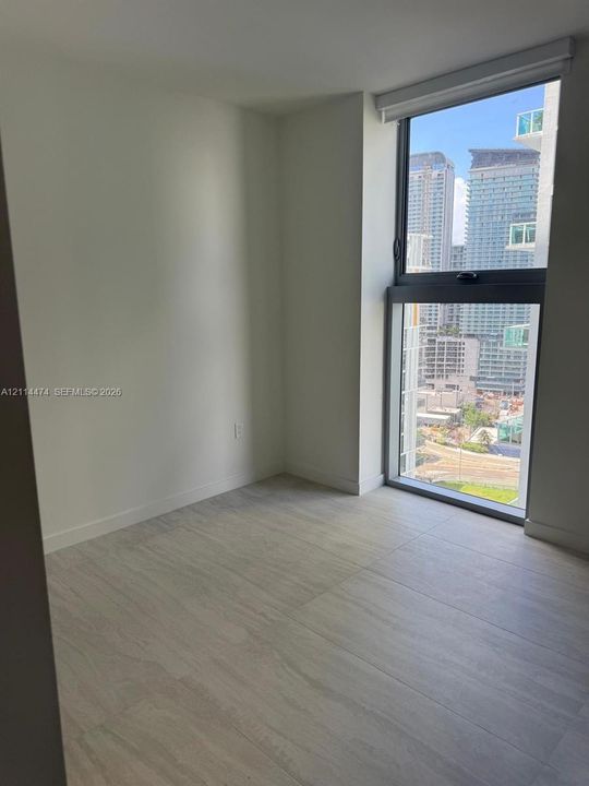 Neutral interior space featuring large-format tile flooring, floor-to-ceiling windows, and urban cityscape backdrop