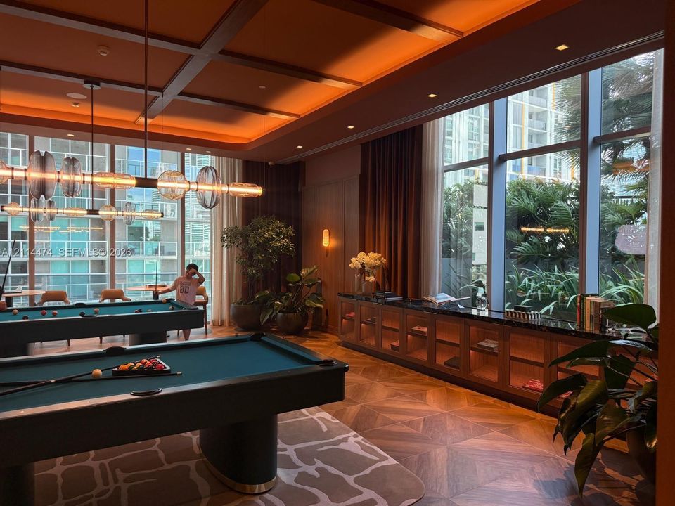Coffered ceiling featuring recessed lighting, expansive floor-to-ceiling windows, built-in lower cabinetry with stone surfacing, and intricate geometric-patterned wood-finish flooring