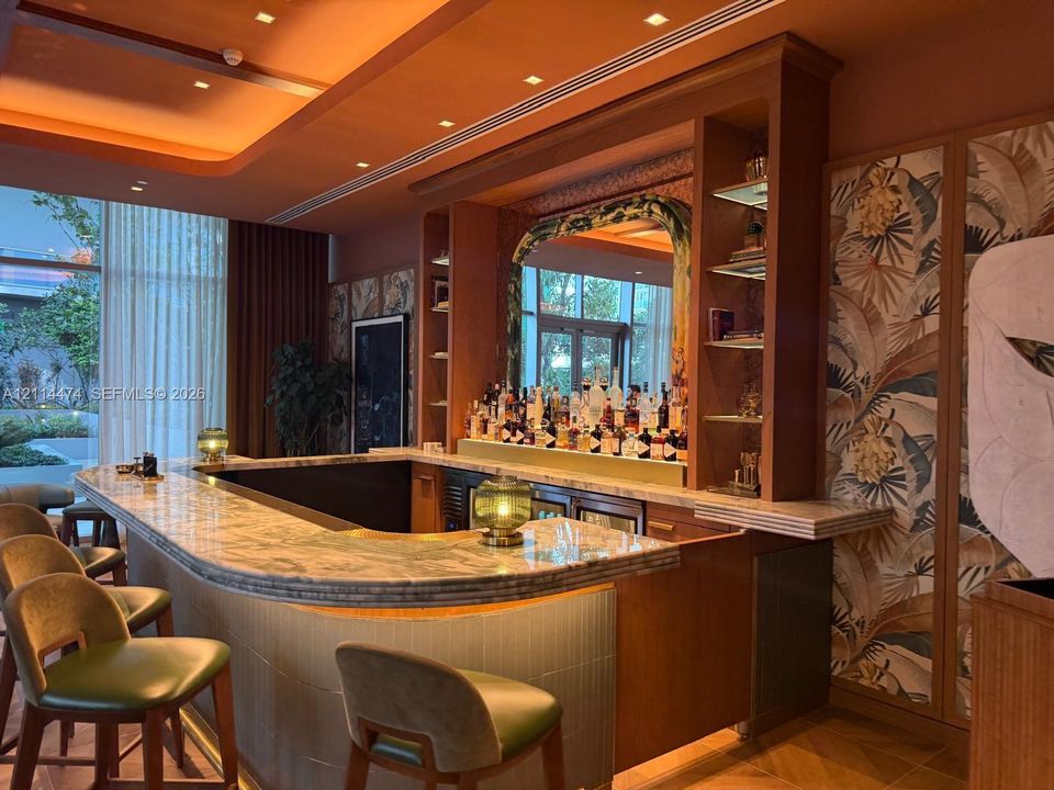 Custom bar featuring a stone countertop, built-in wooden cabinetry, recessed tray ceiling lighting, and decorative wall paneling