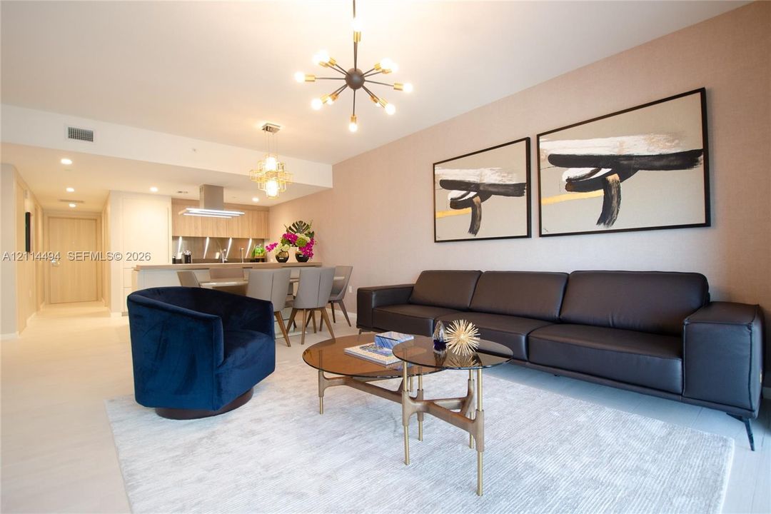 Open-concept living space featuring light-toned wood-finish flooring, a contemporary multi-arm sputnik chandelier, and recessed lighting