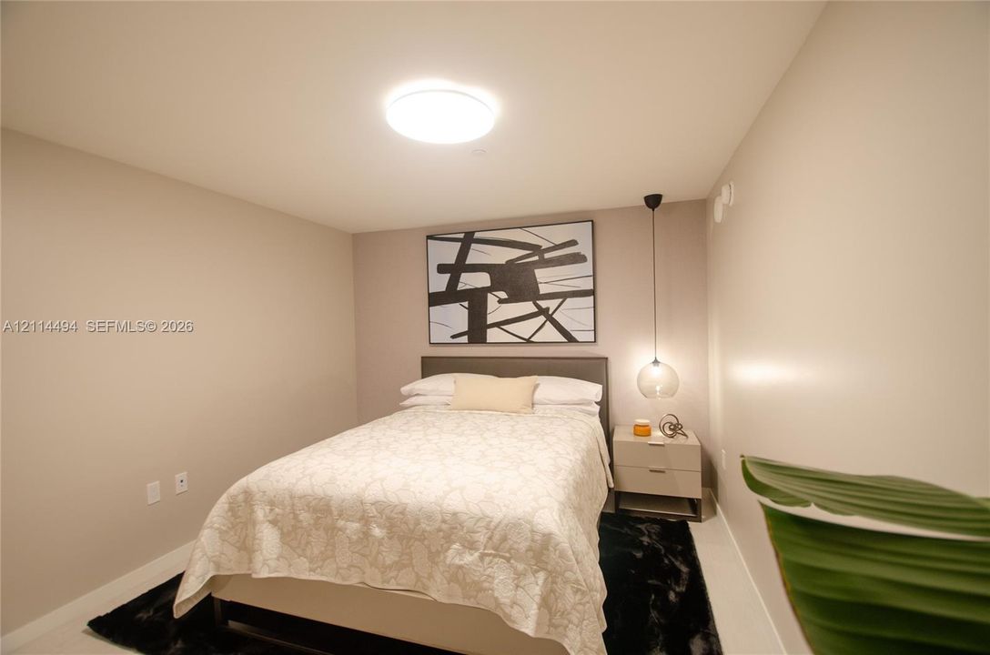 Neutral-toned room featuring a central flush-mount ceiling light and a suspended glass globe pendant light