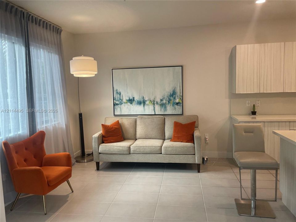 Large-format light-toned floor tile, vertical-grain cabinetry with integrated hardware, and expansive window with ceiling-mounted drapery track