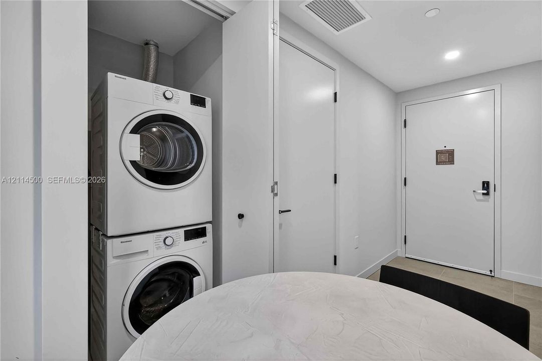 Entryway featuring large-format tile flooring, recessed ceiling lighting, and a floor-to-ceiling wood-finish cabinetry wall with matte black hardware