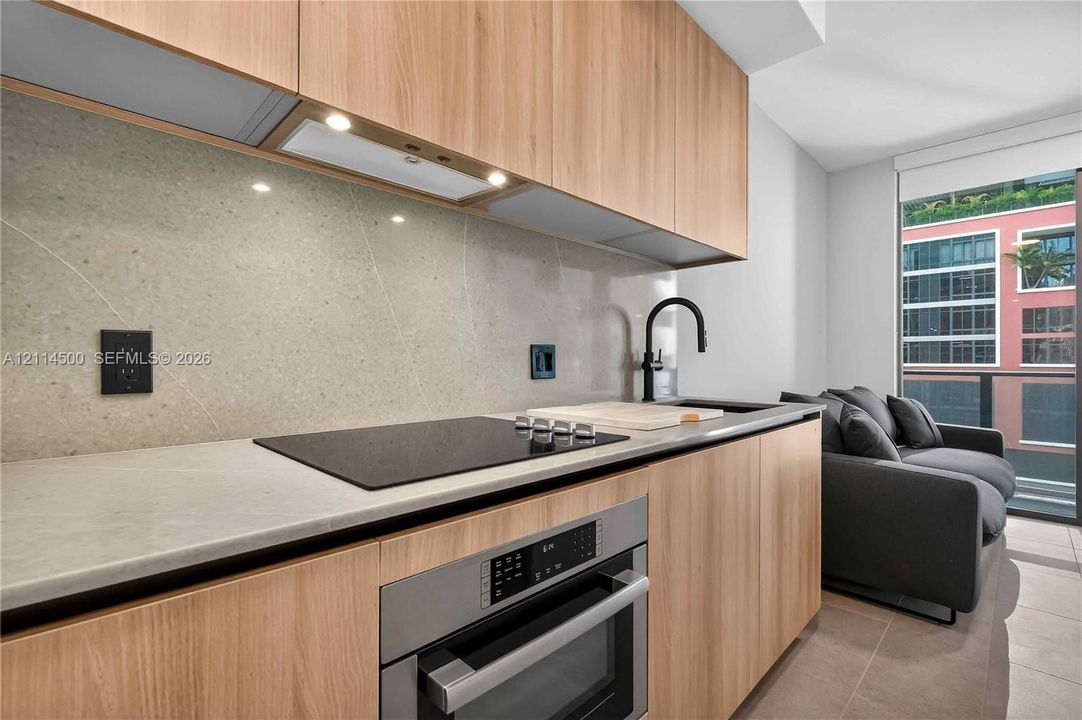 Floor-to-ceiling sliding glass doors, neutral tile flooring, and a private balcony with black metal railings