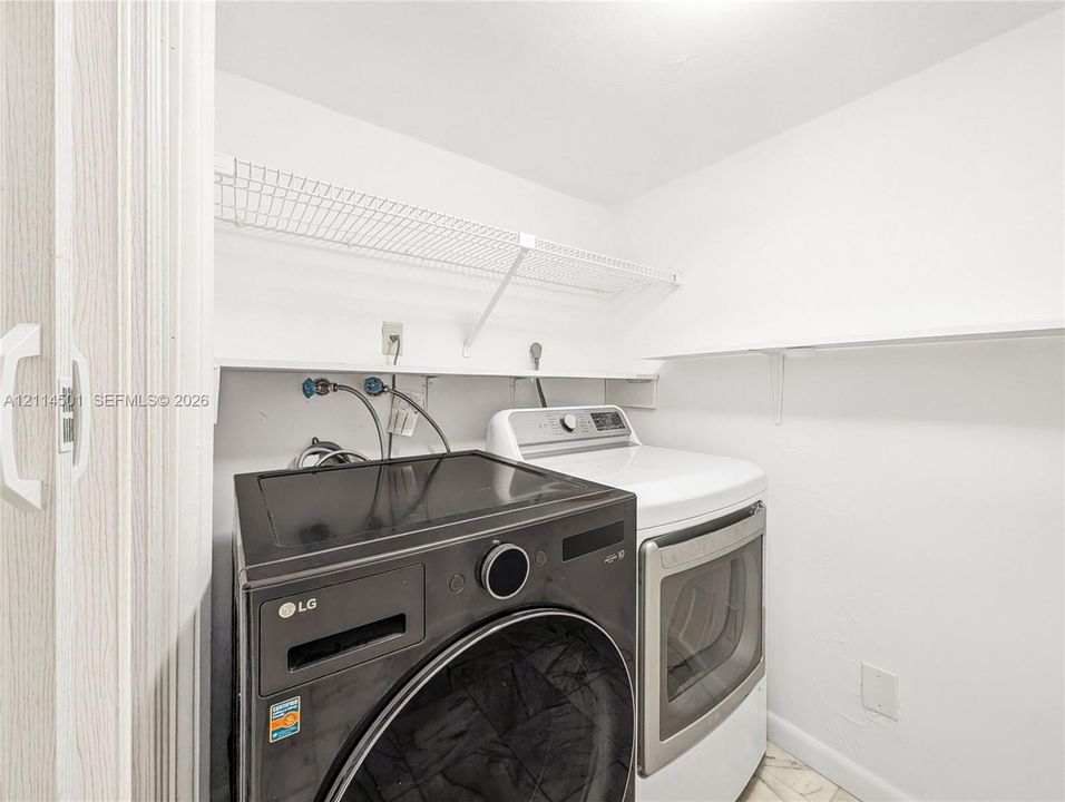 Laundry area featuring white built-in shelving and wire storage rack