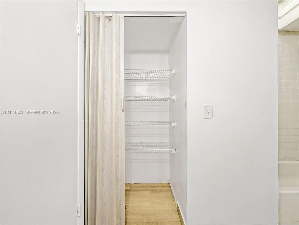 Storage closet featuring a wood-finish folding door, white wire shelving, and wood-finish flooring