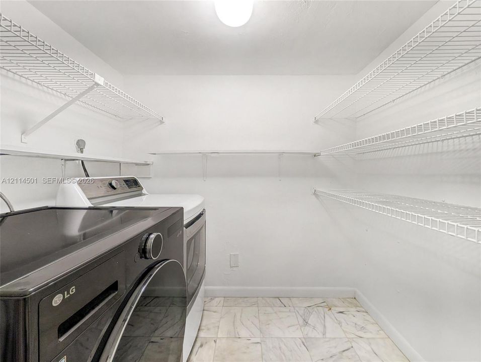 Laundry space featuring tile flooring and integrated wall-mounted white wire shelving