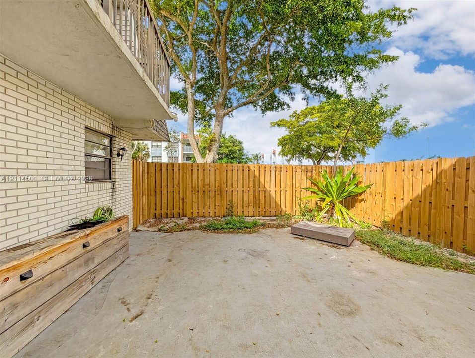 Private courtyard featuring a concrete patio, wood-style privacy fencing, and an elevated wooden planter box