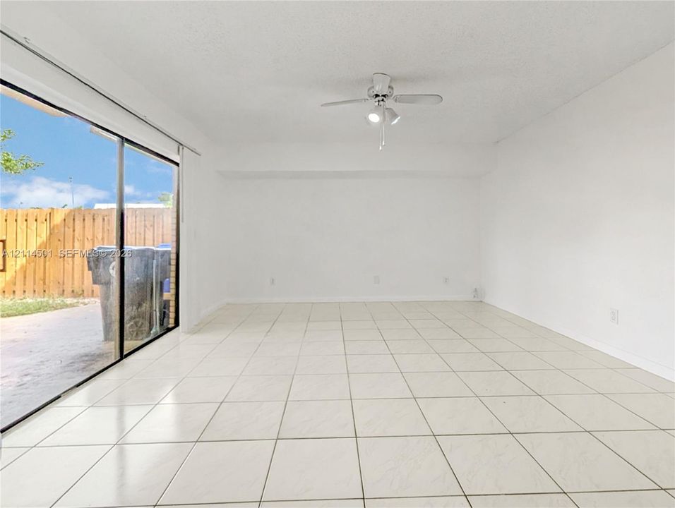 Interior space featuring neutral wall tones, large-format tile flooring, a ceiling-mounted fan with integrated lighting, and sliding glass doors
