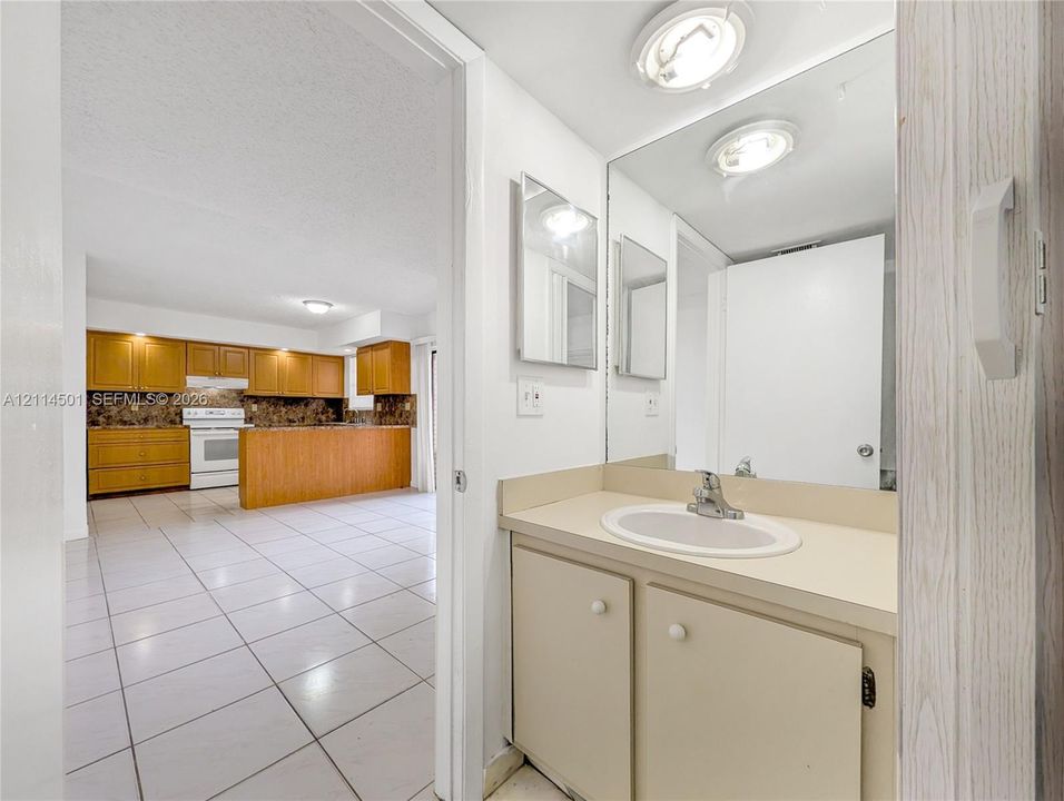 Bathroom vanity featuring a solid-surface countertop with an integrated basin and wooden cabinetry, accompanied by a full-width mirror and circular ceiling-mounted lighting