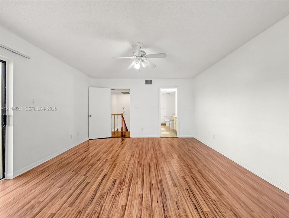 Interior room featuring wood-finish flooring, a ceiling fan with integrated lighting, and a sliding glass door