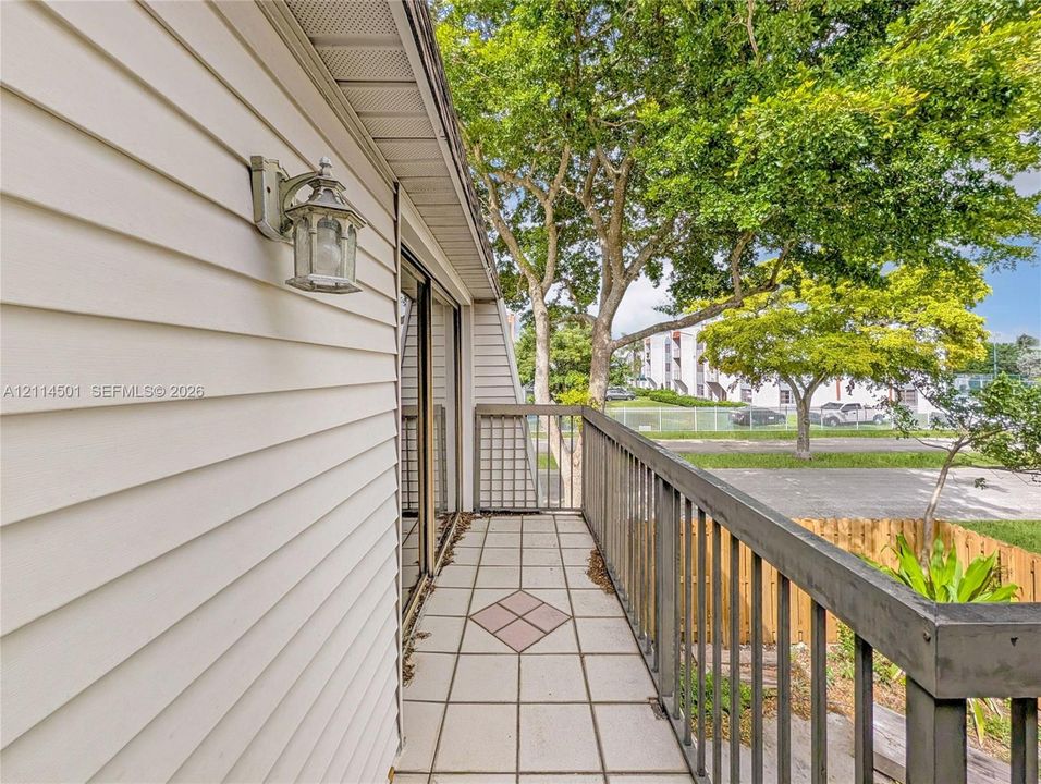 Balcony featuring horizontal siding, tiled flooring with decorative inlays, metal railing, and wall-mounted exterior lighting
