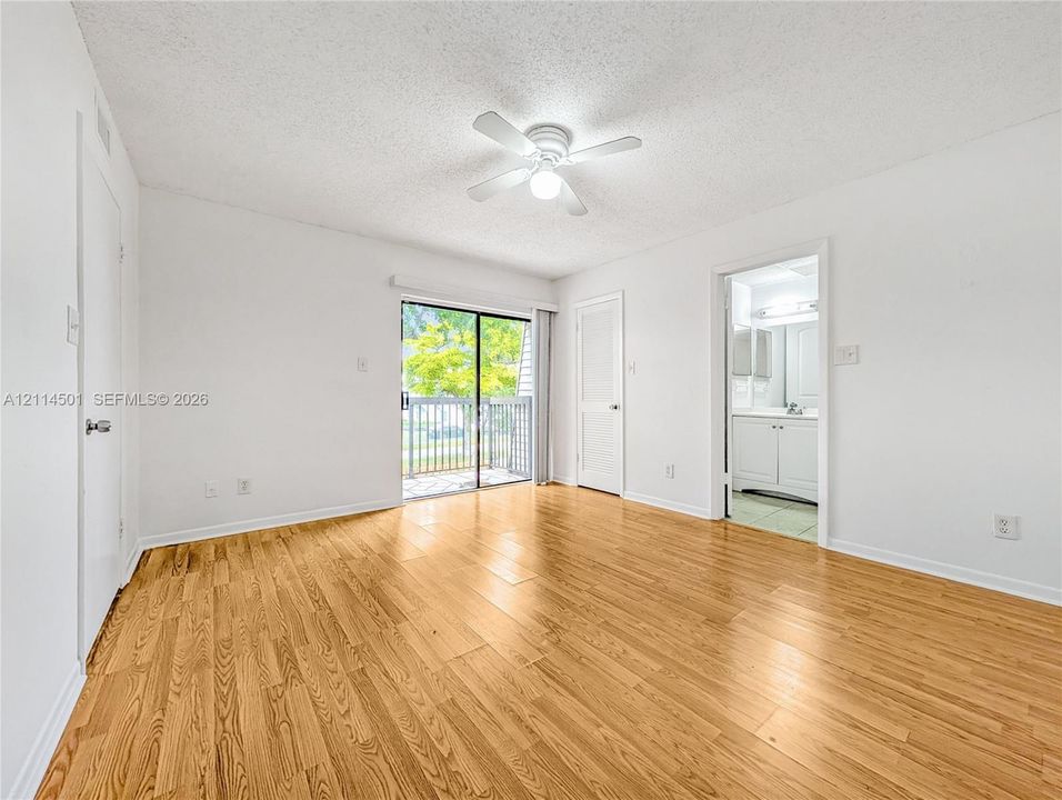 Wood-finish flooring, ceiling fan with integrated light, sliding glass door, and private balcony
