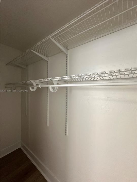 White wire shelving system featuring dual-tier hanging rods and adjustable track-mounted supports