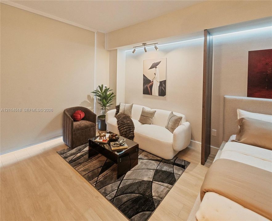 Wood-finish flooring, recessed LED cove lighting, and a vertical wood-paneled room divider