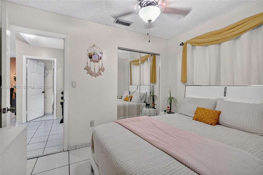 Ceramic tile flooring, ceiling fan with integrated lighting, and mirrored closet doors