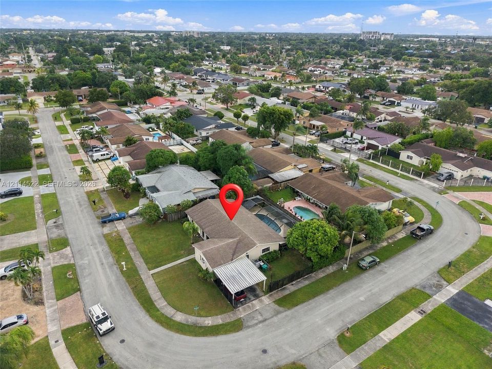Corner lot residence featuring a screened-in swimming pool, covered carport, and mature landscaping