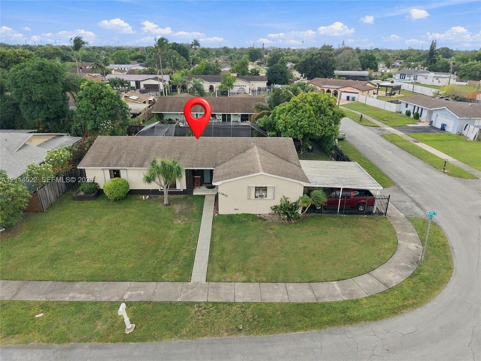 Single-story residence featuring a low-slope roof, an attached carport, a concrete walkway, and a landscaped front lawn on a corner lot