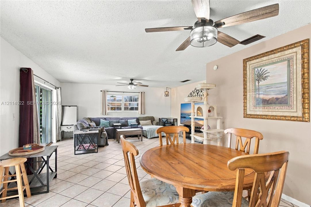 Living area featuring ceramic tile flooring, dual ceiling fans with integrated lighting, and sliding glass patio doors