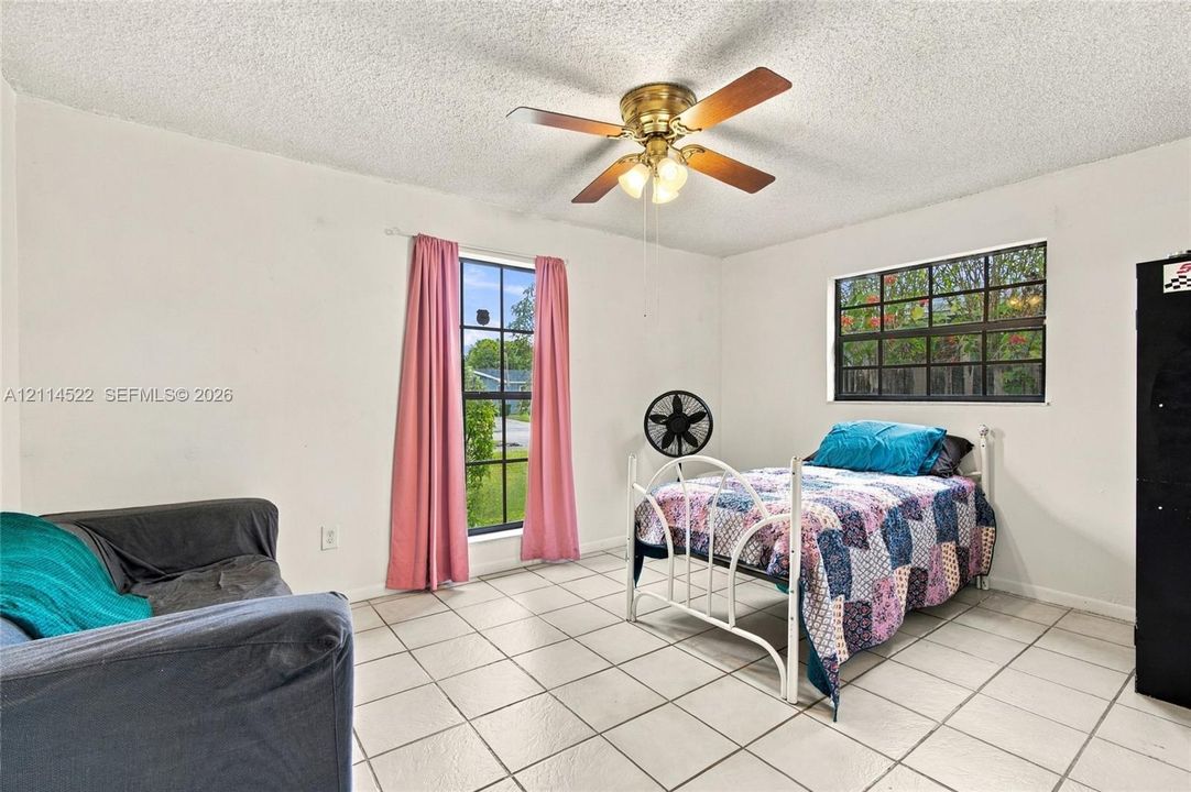 Neutral interior featuring large-format ceramic tile flooring, multi-pane windows, and a ceiling-mounted light fixture with integrated fan