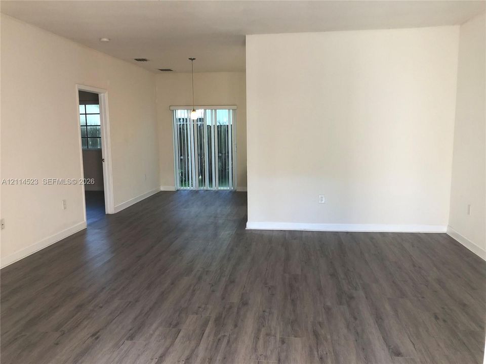 Open floor plan featuring wood-finish flooring, neutral wall paint, and vertical sliding glass doors