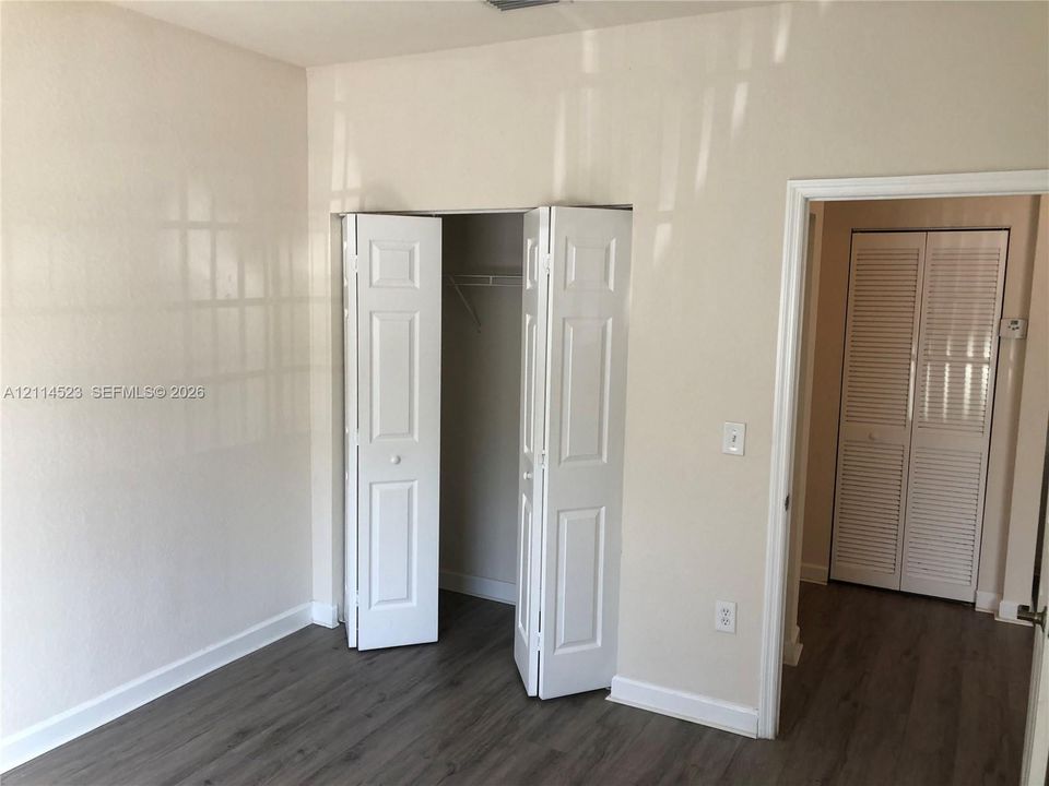 Wood-finish flooring, six-panel bi-fold closet doors, and louvered double closet doors