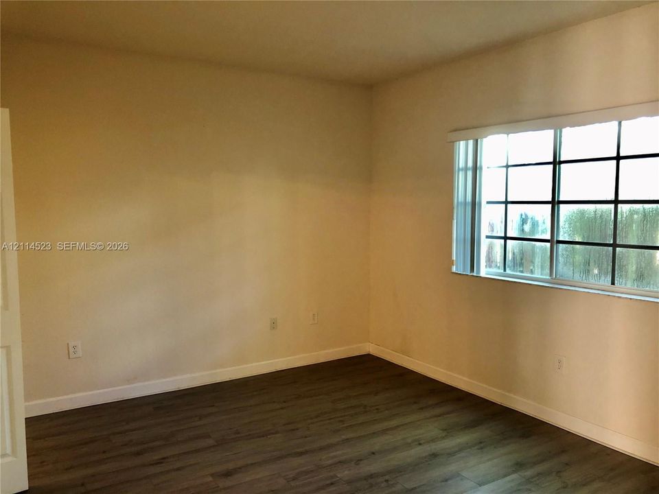 Neutral interior featuring wood-finish flooring and a multi-pane grid window