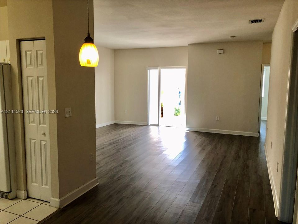 Open-concept space featuring wood-finish flooring, a glass-panel exterior door, and a single pendant light fixture