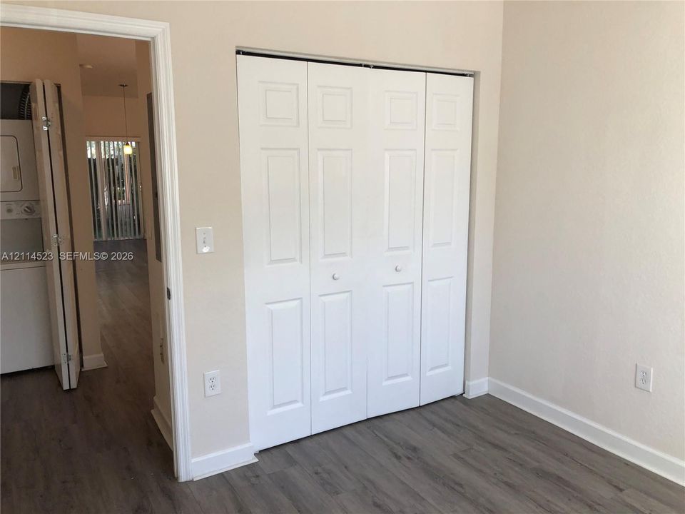Four-panel folding closet doors with white finish, wood-finish flooring, and neutral wall paint