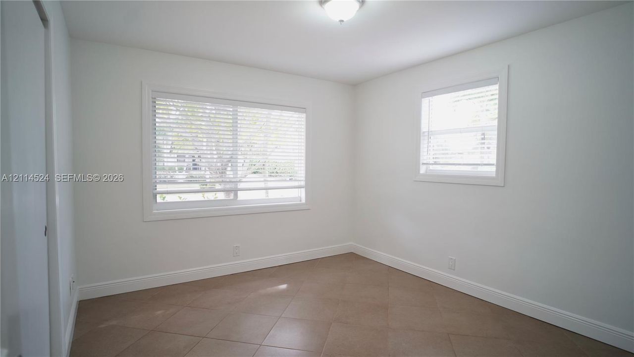Neutral-toned ceramic tile flooring, dual-pane windows with horizontal blinds, and a dome-style flush mount ceiling light fixture
