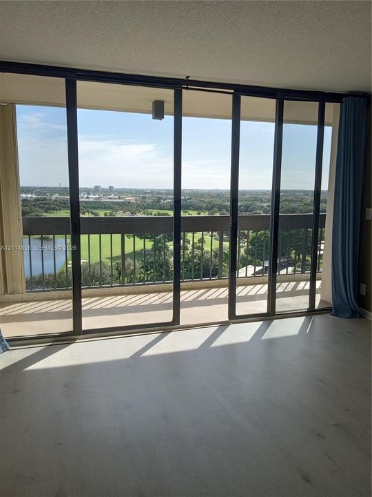 Floor-to-ceiling sliding glass doors opening to a private balcony with metal railing, wood-finish flooring, and expansive natural scenery