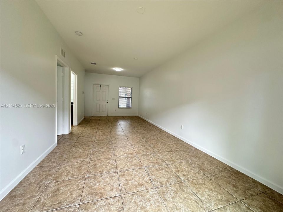 Open interior space featuring light-toned tile flooring, recessed lighting, and a neutral color palette