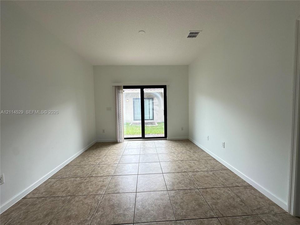 Interior space featuring neutral wall tones, large-format tile flooring, and black-framed sliding glass doors