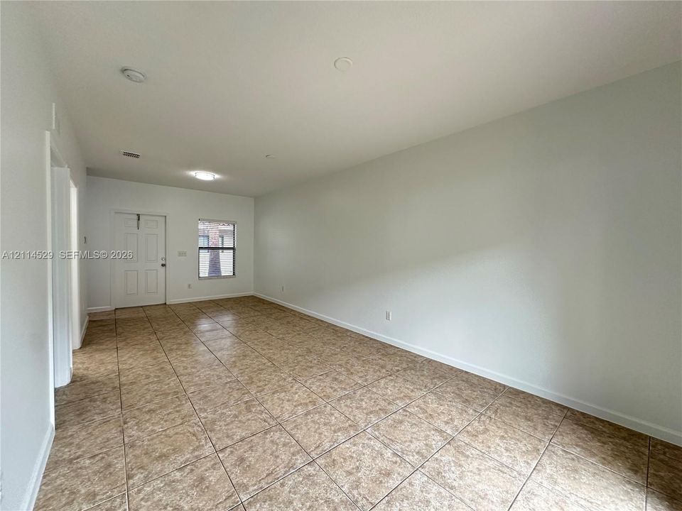 Neutral-toned walls, tile flooring, flush-mount lighting, and an exterior door with a windowed panel