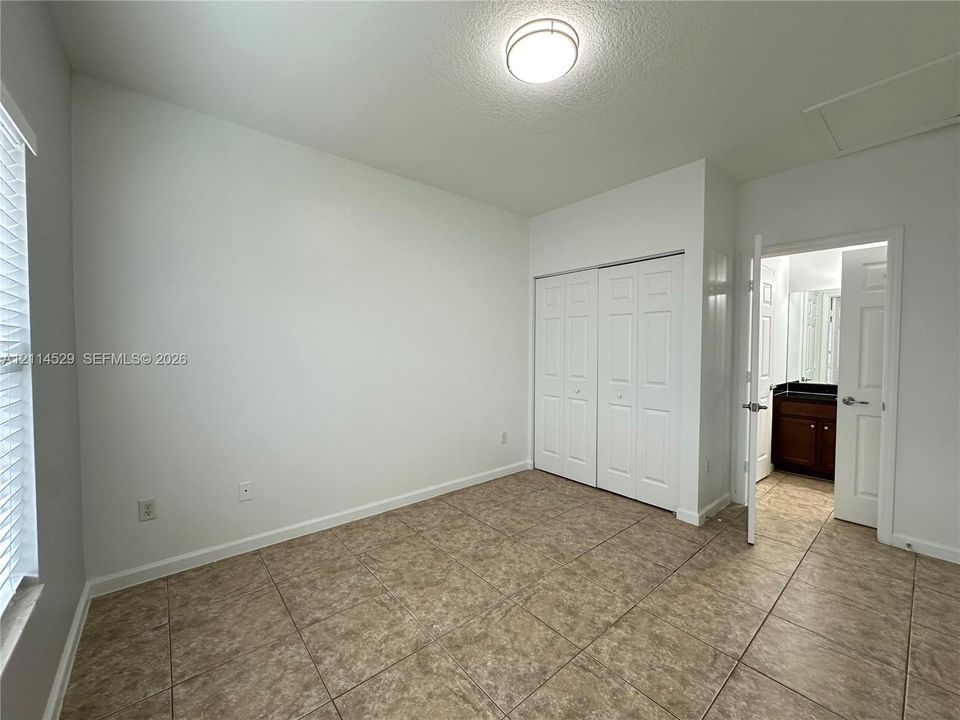 Room featuring ceramic tile flooring, double-door closet, recessed lighting fixture, and window with blinds