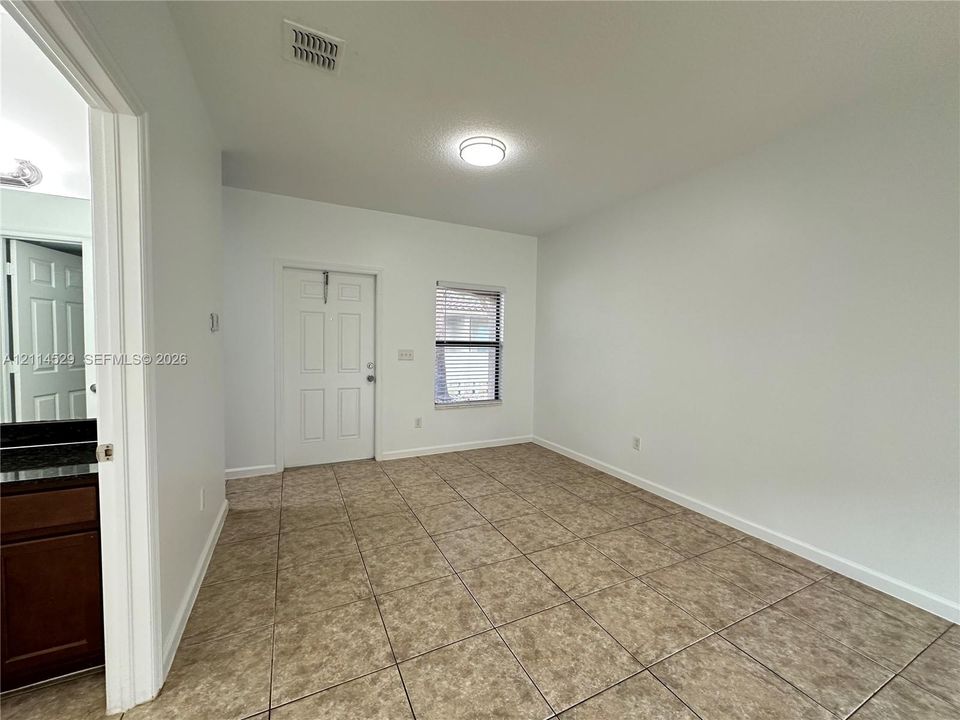 Interior space featuring neutral-toned tile flooring, a six-panel door, and a flush-mount ceiling light fixture
