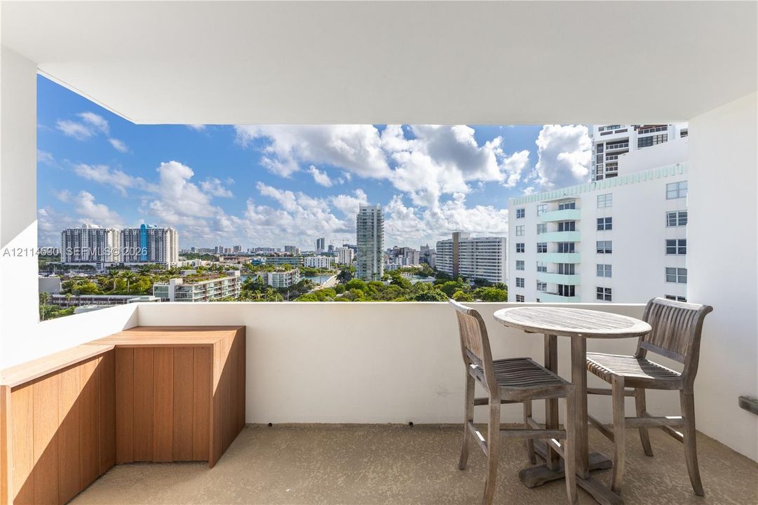 Covered balcony featuring concrete flooring, a custom wood-finish built-in storage unit, and expansive urban scenery