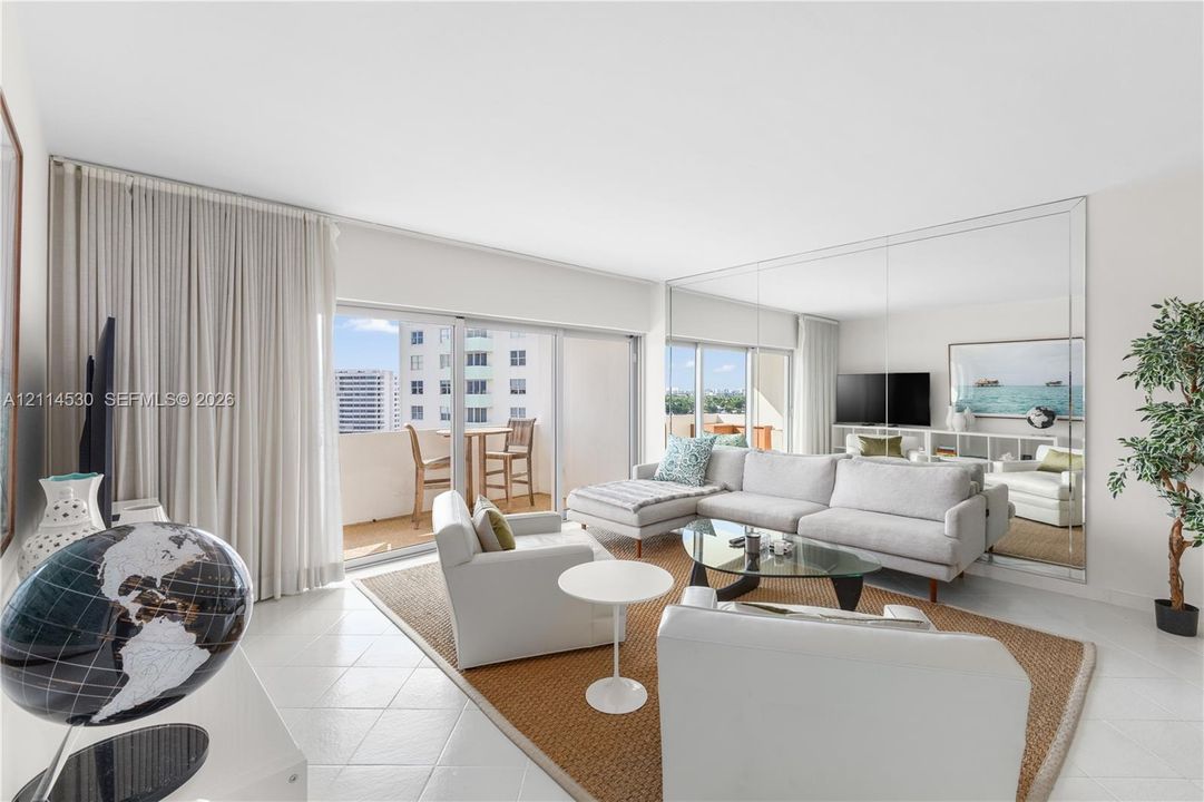 Light-filled living area featuring floor-to-ceiling glass sliding doors, neutral tile flooring, and a full-height mirrored wall