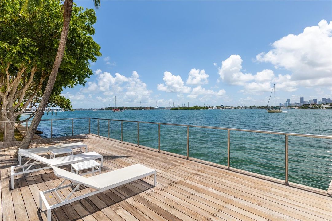 Waterfront wood deck featuring stainless steel railings and mature trees