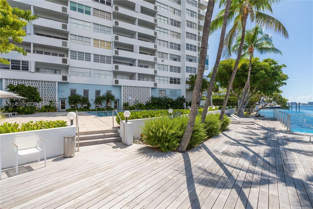 Waterfront terrace featuring wood-plank decking, a swimming pool, concrete stairs, and perimeter railings