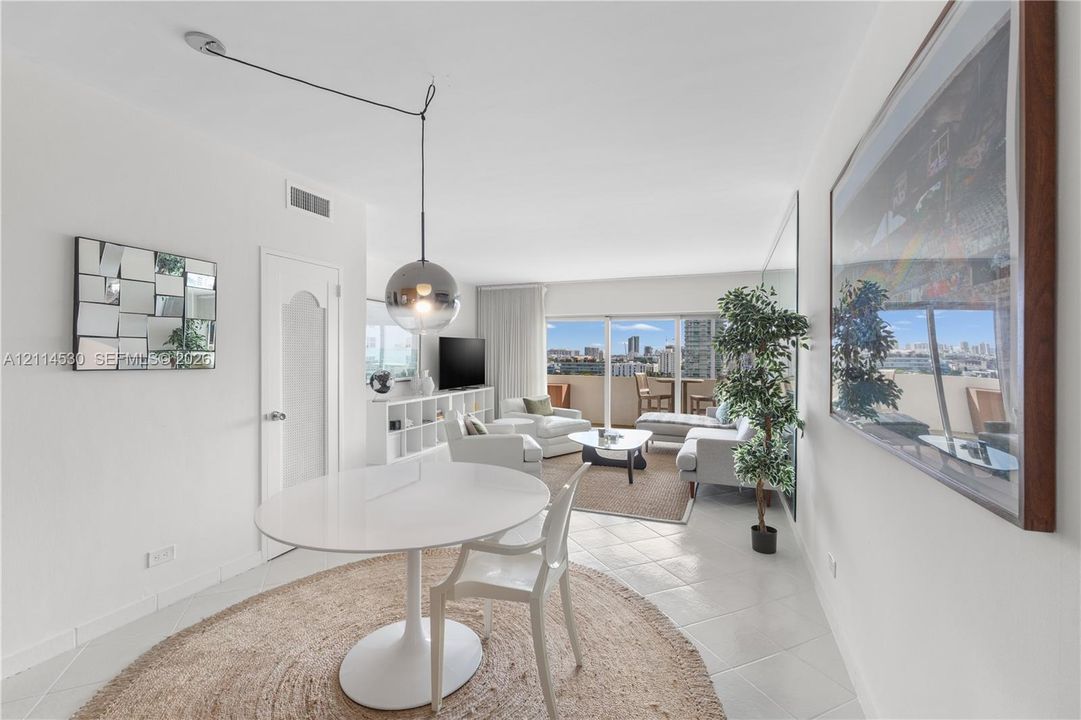Living area featuring large-format ceramic tile flooring, floor-to-ceiling glass sliding doors, a polished metallic spherical pendant light, and a full-wall mirror