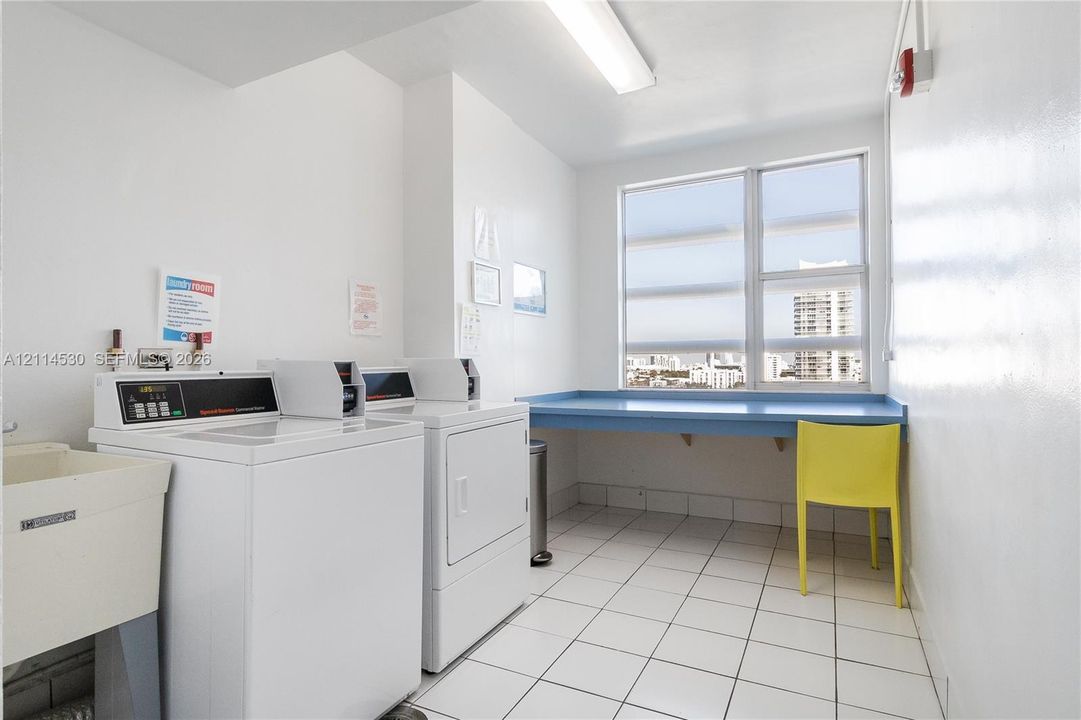 Laundry room featuring white tile flooring, large multi-pane windows, and a built-in folding counter