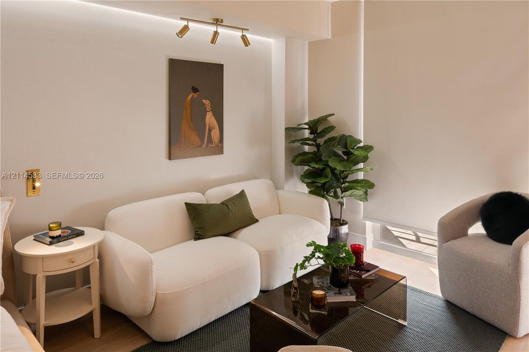 Neutral walls featuring recessed cove lighting, a three-head adjustable gold-tone track light fixture, and a wall-mounted gold-tone sconce