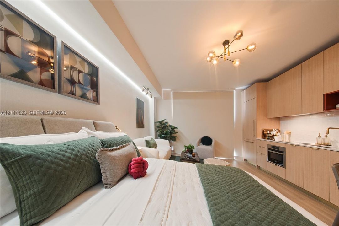 Open-concept living space featuring flat-panel wood-finish cabinetry, built-in stainless steel appliances, recessed linear cove lighting, modern multi-arm chandelier, and wood-finish flooring