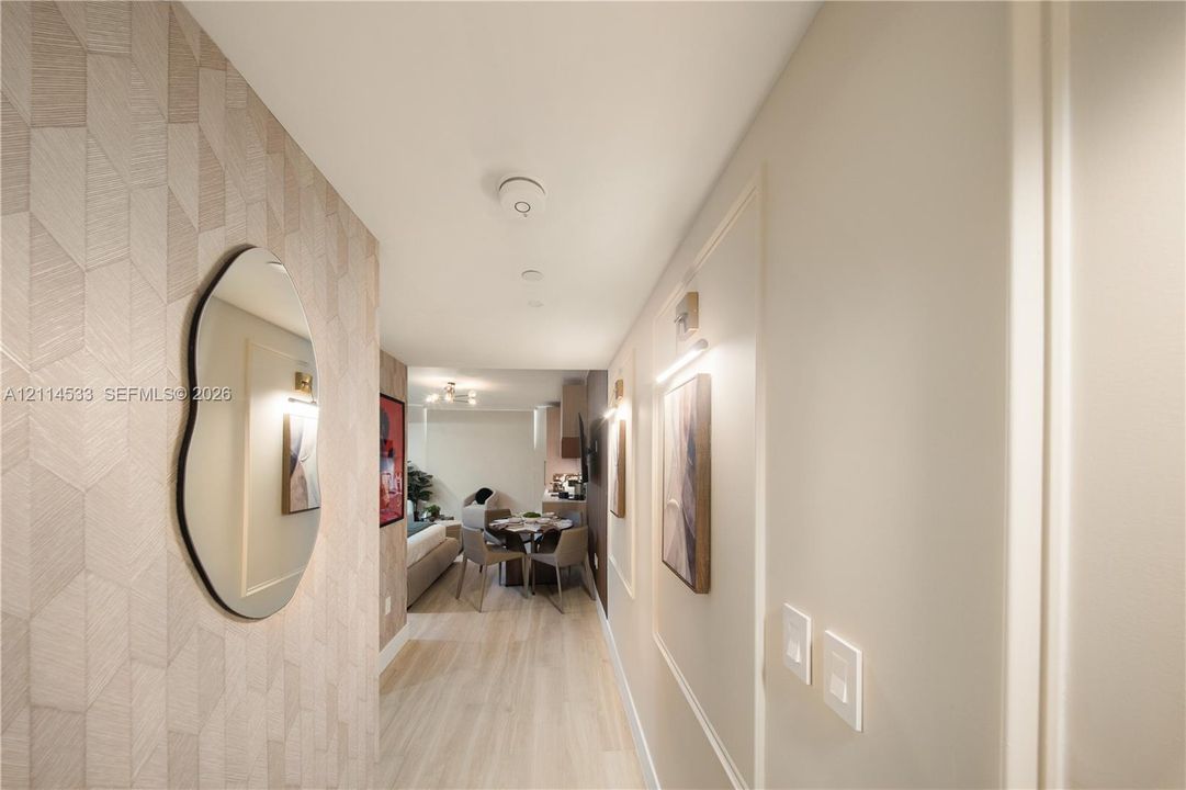 Entryway featuring geometric patterned wall covering, wood-finish flooring, and recessed wall paneling with integrated wall-mounted lighting