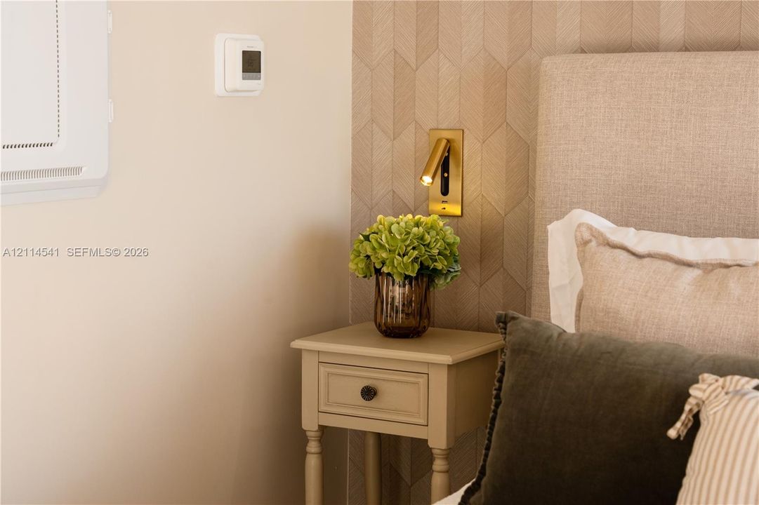 Textured geometric wall treatment, wall-mounted brass reading light, and neutral-toned wall finish