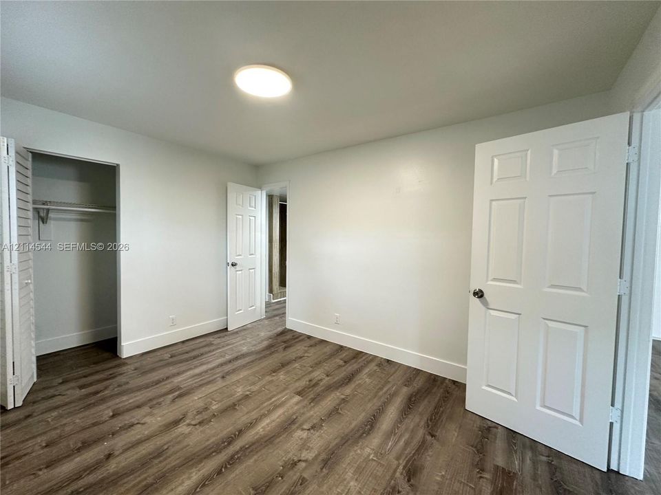 Interior space featuring wood-finish flooring, six-panel interior doors, and a closet with louvered double doors