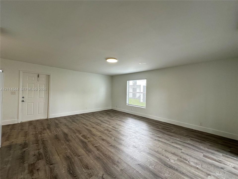 Interior space featuring wood-finish flooring, white walls, a flush-mount ceiling light, and a single-panel window
