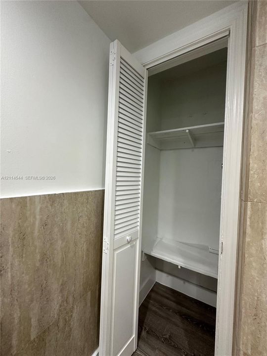 Closet featuring white louvered bi-fold doors, interior shelving, and wood-finish flooring